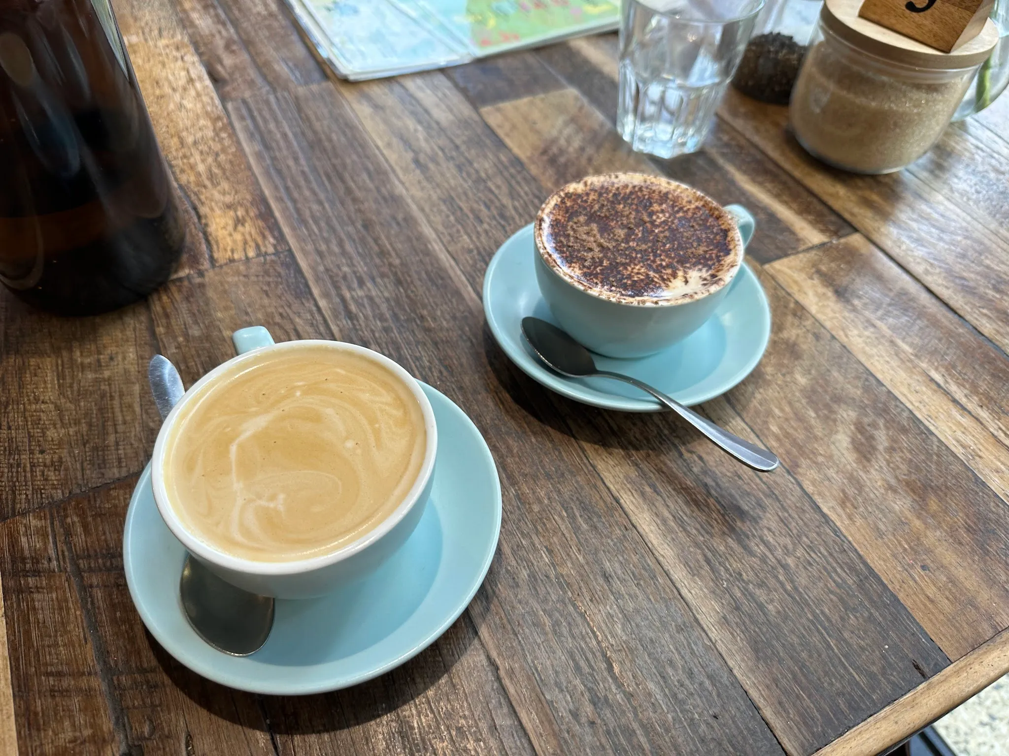 Flat white and cappuccino on blue saucers at a timber cafe table