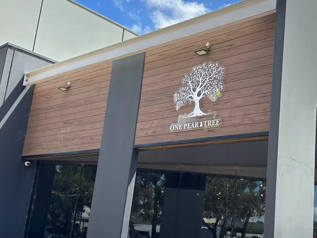 One Pear Tree cafe exterior with white tree logo on timber-clad facade under blue sky