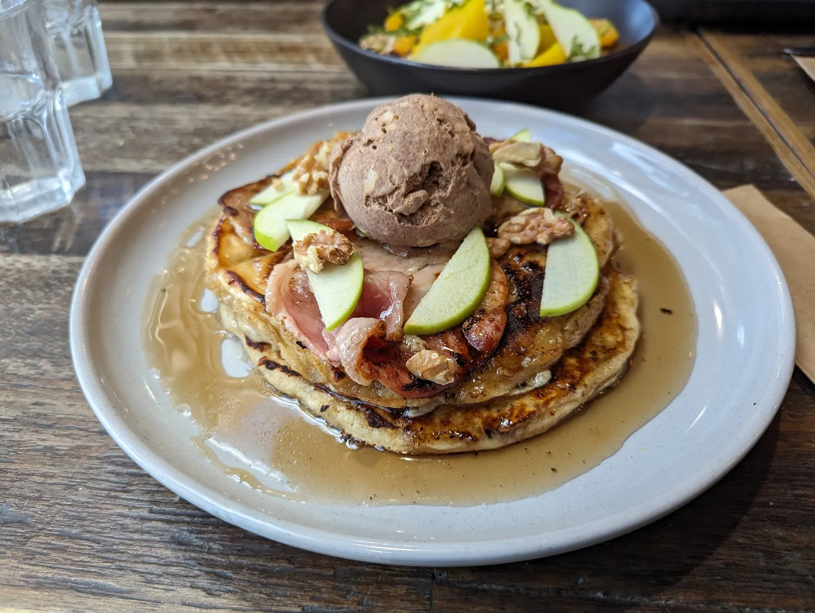 Stack of pancakes with chocolate ice cream, apple and caramelised bacon