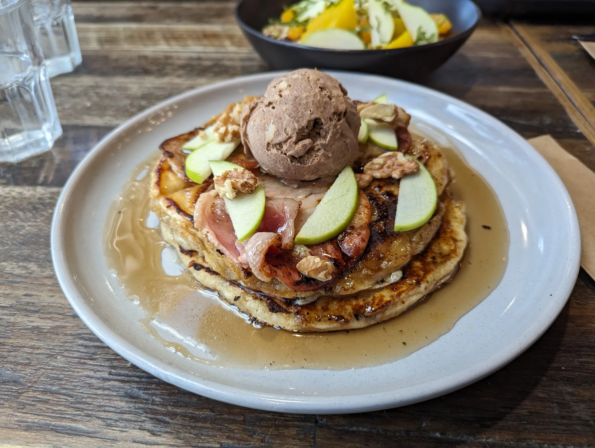 Stack of pancakes with chocolate ice cream, apple and caramelised bacon