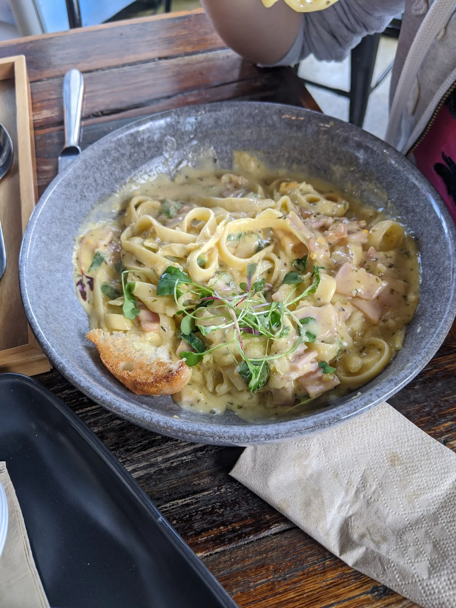Creamy fettuccine with smoked salmon and herbs in a stone bowl with toasted sourdough