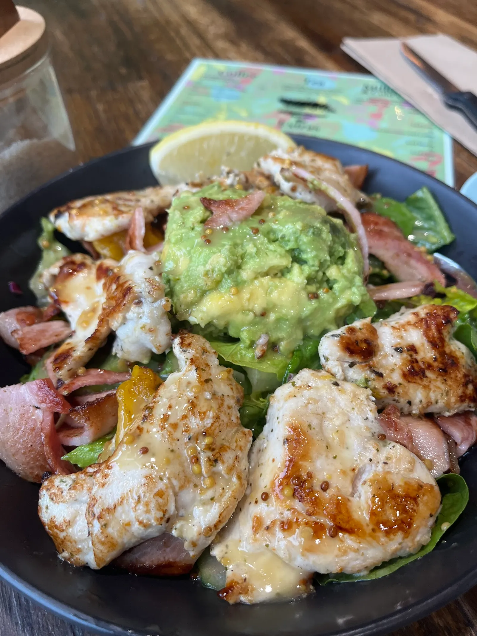 Grilled chicken salad with guacamole, bacon and capsicum in a dark skillet