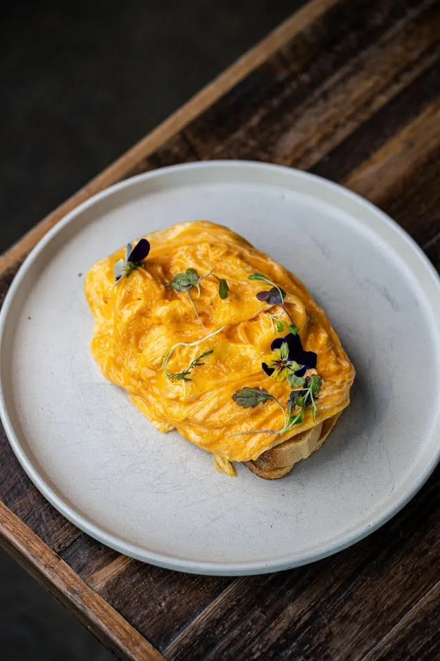 Silky scrambled eggs with edible viola flowers on sourdough toast